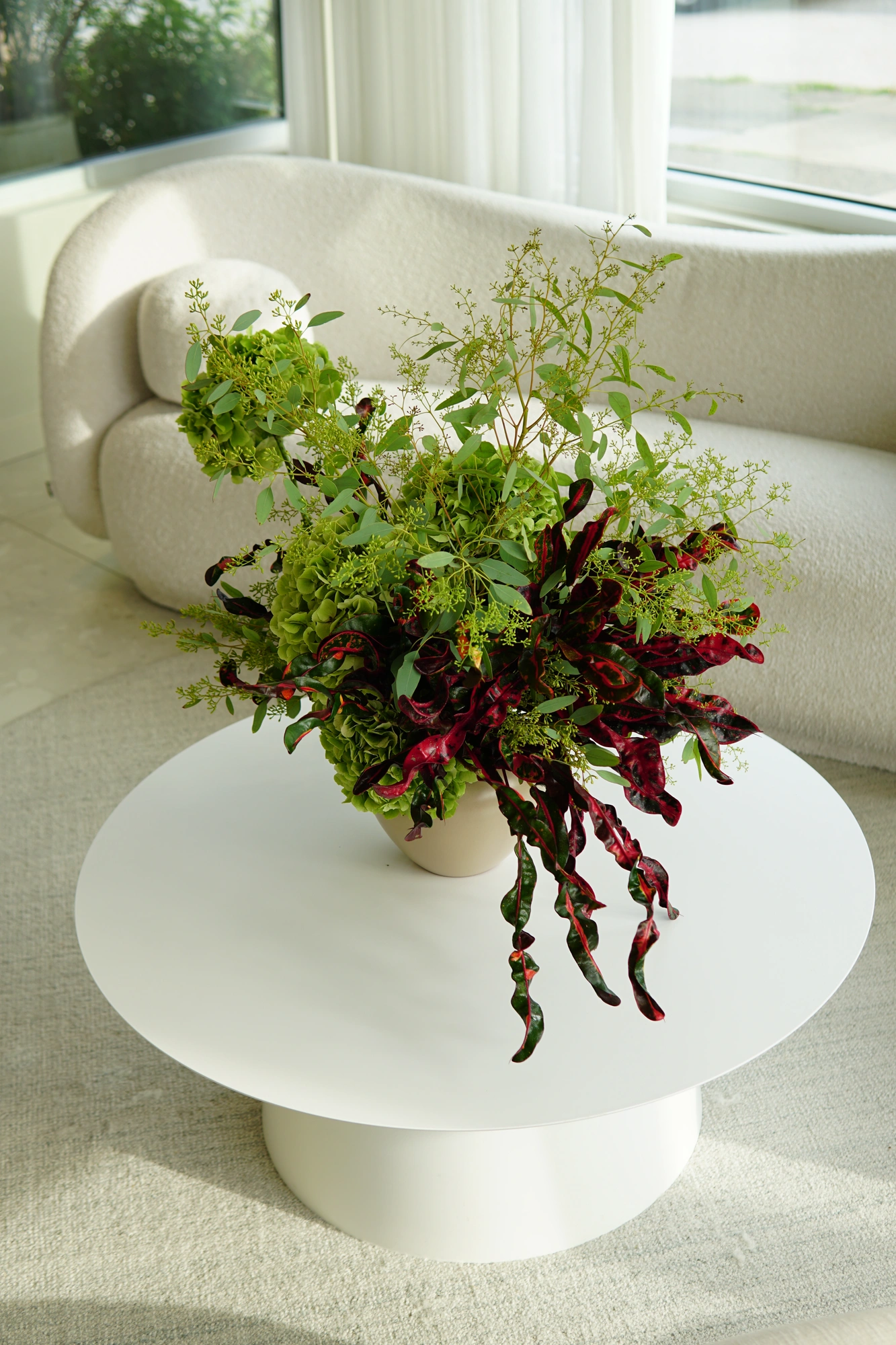 Green hydrangea and burgundy croton on a white lounge table