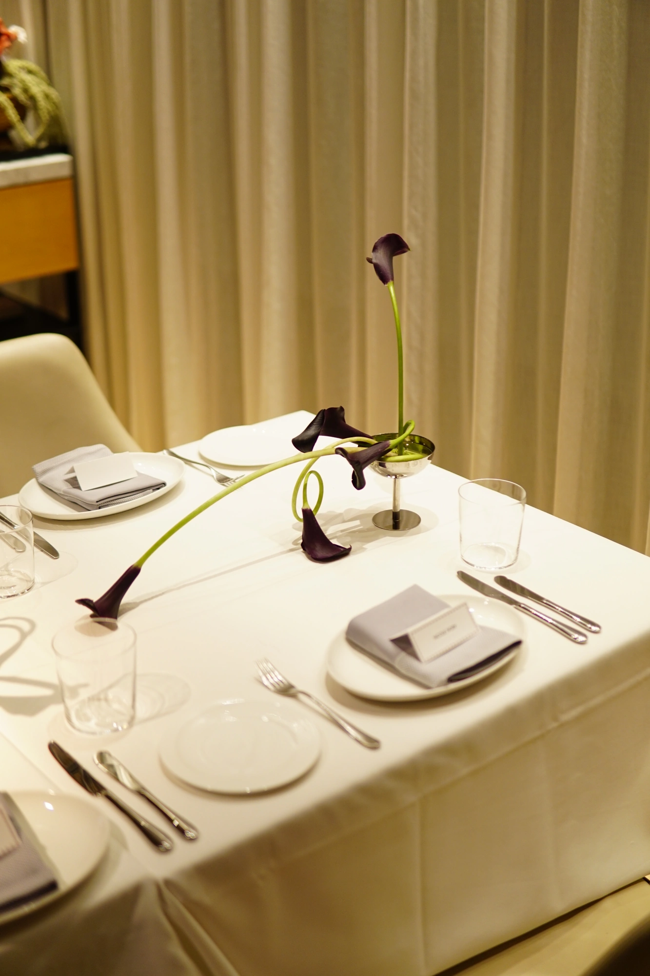 Dark calla lily centrepiece in a steel cup on a white wedding table